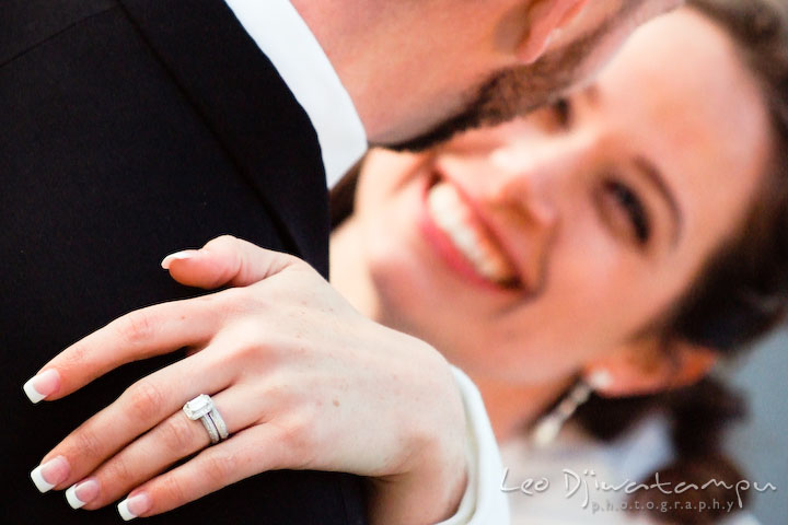 Bride smiling, looking at groom, showing wedding and engagement ring.