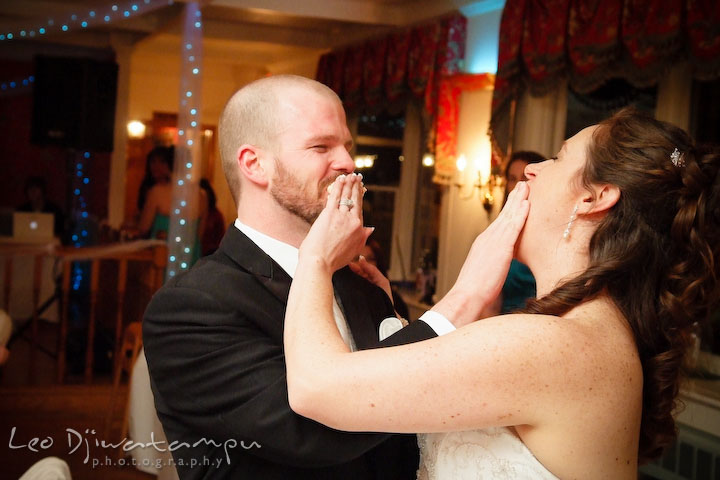 Bride and groom shoving cake to each other's mouth. Kitty Knight House Georgetown Chestertown MD Wedding Photographer