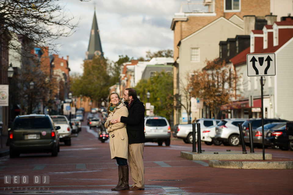 Engaged man cuddling his fiancée on the Main Street with the church circle in the background. Annapolis Eastern Shore Maryland pre-wedding engagement photo session at downtown, by wedding photographers of Leo Dj Photography. http://leodjphoto.com