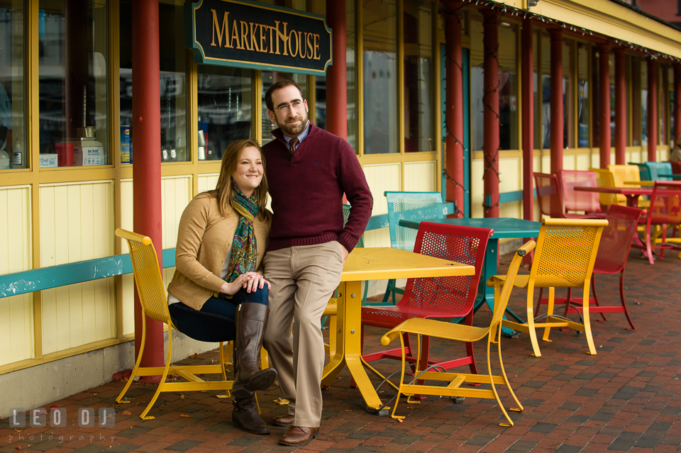 Engaged couple sitting by the tables outside Market House and enjoying the view of downtown dock. Annapolis Eastern Shore Maryland pre-wedding engagement photo session at downtown, by wedding photographers of Leo Dj Photography. http://leodjphoto.com