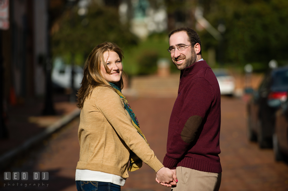 Engaged couple strolling along brick road and holding hands. Annapolis Eastern Shore Maryland pre-wedding engagement photo session at downtown, by wedding photographers of Leo Dj Photography. http://leodjphoto.com