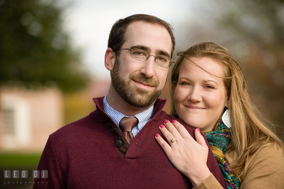 Engaged man embraced by his fiance smiling and posing for the camera. Annapolis Eastern Shore Maryland pre-wedding engagement photo session at downtown, by wedding photographers of Leo Dj Photography. http://leodjphoto.com