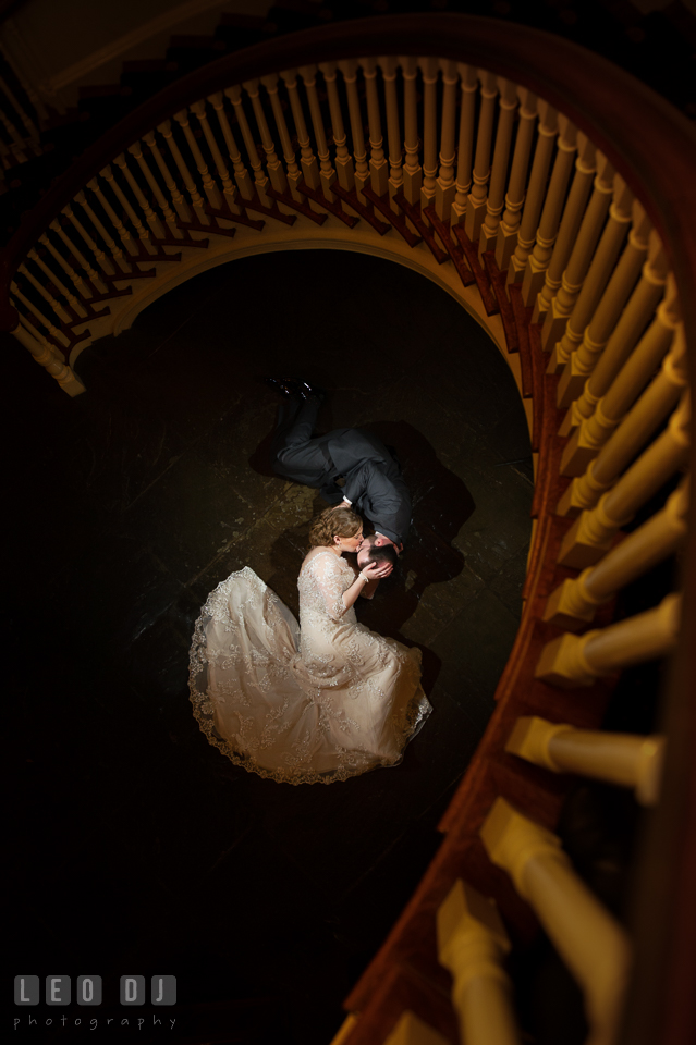 Bride and Groom lying on the floor kissing, framed by the circular stairway. The Tidewater Inn wedding, Easton, Eastern Shore, Maryland, by wedding photographers of Leo Dj Photography. http://leodjphoto.com