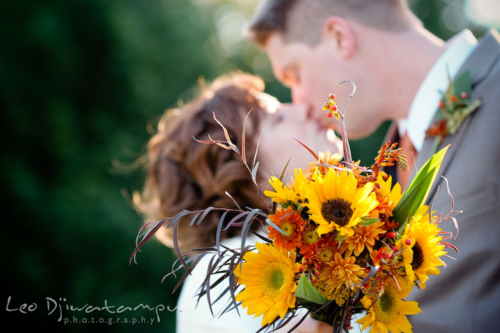 Bride holding bouquet while bride and groom kissed in the background. Rock Hall, Chestertown, Kingstown, and Georgetown Maryland wedding photographer, Leo Dj Photography