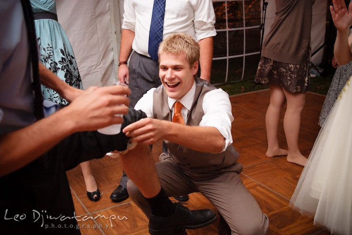 Groomsman putting garter on another guy's leg. Rock Hall, Chestertown, Kingstown, and Georgetown Maryland wedding photographer, Leo Dj Photography