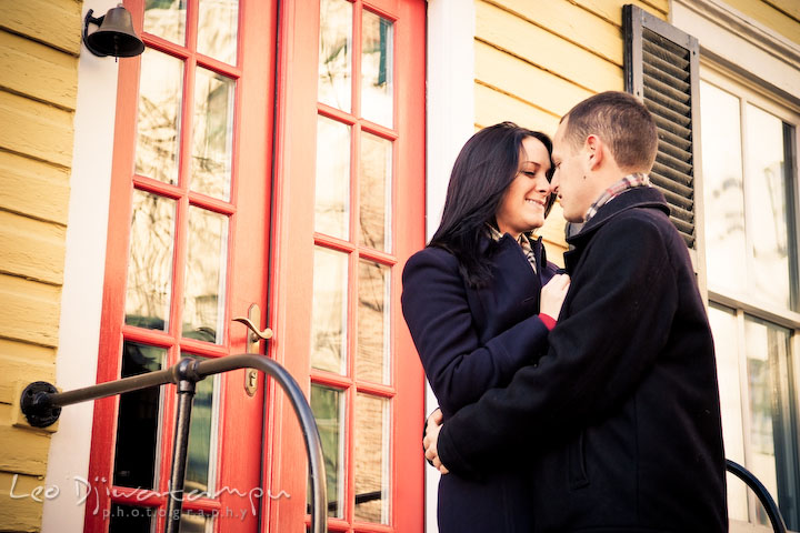 engaged couple in front of a red door, yellow house. Urban City Pre-wedding Engagement Photographer Annapolis MD