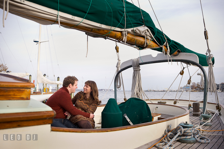 Engaged girl cuddling with her fiancé on a sailboat. Pre-wedding engagement photo session at Annapolis, Eastport, Maryland, Quiet Waters Park, by wedding photographers of Leo Dj Photography. http://leodjphoto.com