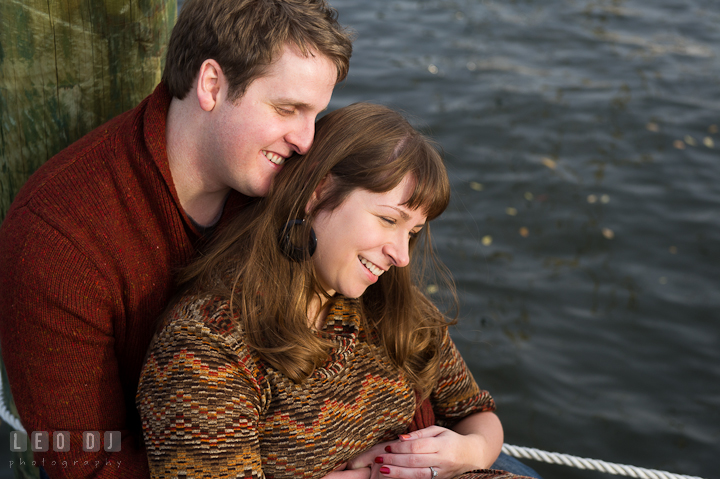 Engaged guy cuddled with his fiancée on the pier. Pre-wedding engagement photo session at Annapolis, Eastport, Maryland, Quiet Waters Park, by wedding photographers of Leo Dj Photography. http://leodjphoto.com
