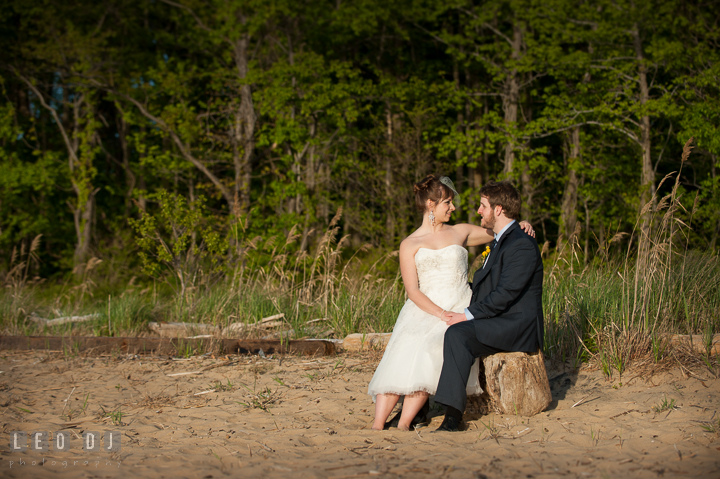 Bride sitting on Groom's lap on the beach. Kent Island Maryland Matapeake Beach wedding reception party and romantic session photo, by wedding photographers of Leo Dj Photography. http://leodjphoto.com