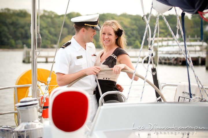 Engaged Navy man cuddling with his fiancee. Pre-wedding engagement photo session USNA US Naval Academy with Navy boat, uniform, vintage clothing, and vintage car