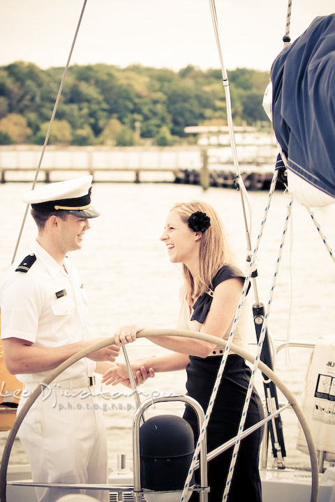 Engaged Midshipman laughing with his fiance. Pre-wedding engagement photo session USNA US Naval Academy with Navy boat, uniform, vintage clothing, and vintage car