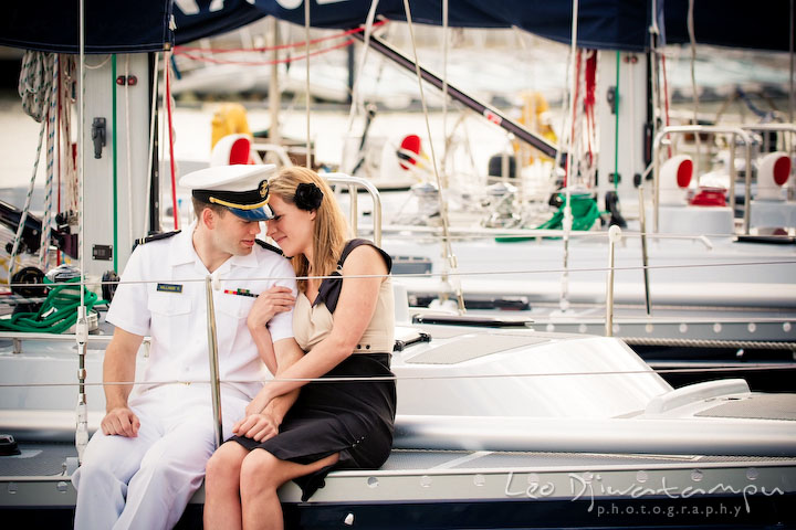 Engaged Midshipman cuddling with his fiancee. Pre-wedding engagement photo session USNA US Naval Academy with Navy boat, uniform, vintage clothing, and vintage car