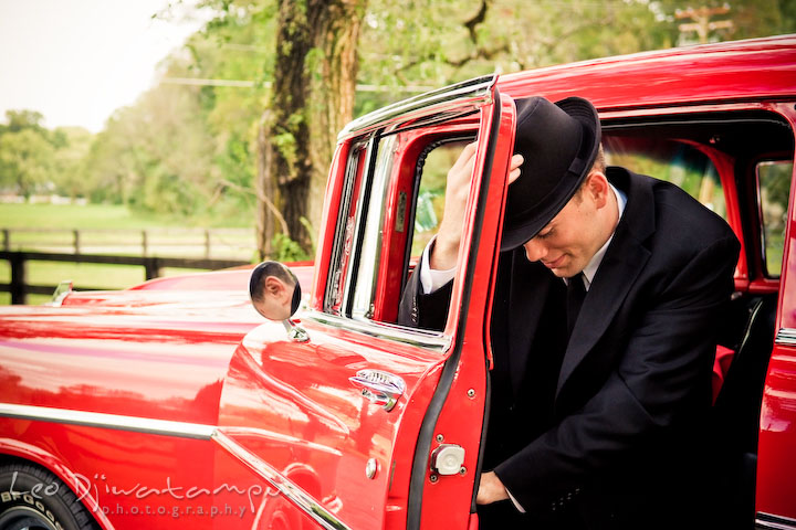 Engaged man coming out of the vehicle putting on his hat. Pre-wedding engagement photography session old antique Chevy Bel Air car, dress, outfit, accessories, suitcases