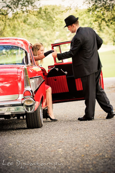 Engaged gentleman holding fiancee's hand helping her to get out. Pre-wedding engagement photography session old antique Chevy Bel Air car, dress, outfit, accessories, suitcases