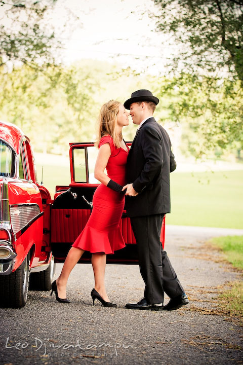 Engaged couple standing close to each other, almost kissed. Pre-wedding engagement photography session old antique Chevy Bel Air car, dress, outfit, accessories, suitcases