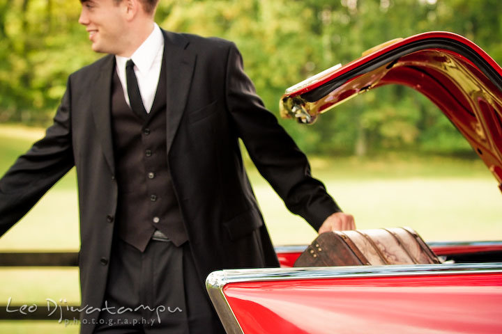 Engaged guy helping his fiancee take out suitcase from car trunk. Pre-wedding engagement photography session old antique Chevy Bel Air car, dress, outfit, accessories, suitcases