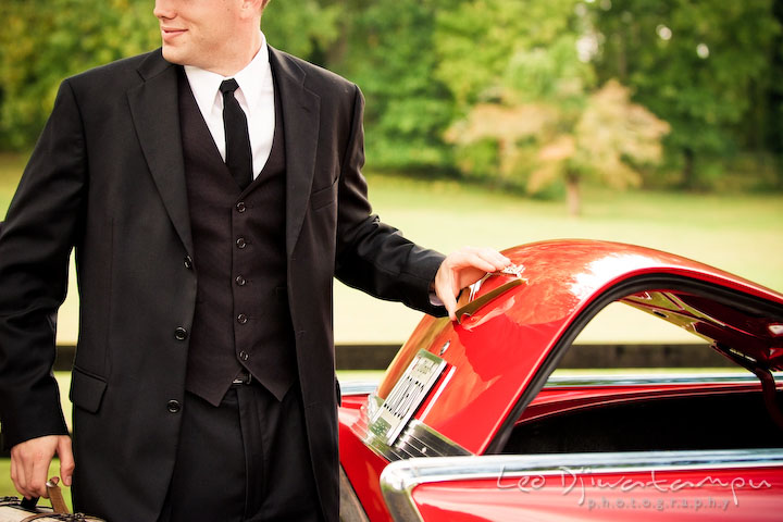 Engaged gentleman closing vehicle trunk. Pre-wedding engagement photography session old antique Chevy Bel Air car, dress, outfit, accessories, suitcases