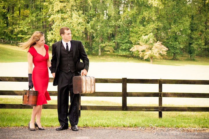 Engaged couple waiting on side of road to hitch a ride. Pre-wedding engagement photography session old antique Chevy Bel Air car, dress, outfit, accessories, suitcases