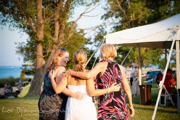 Bride, sister and mother holding each other walking to tent. Cove Creek Country Club, Stevensville, Kent Island, Eastern Shore, Maryland Wedding Photographer, beach wedding photographer