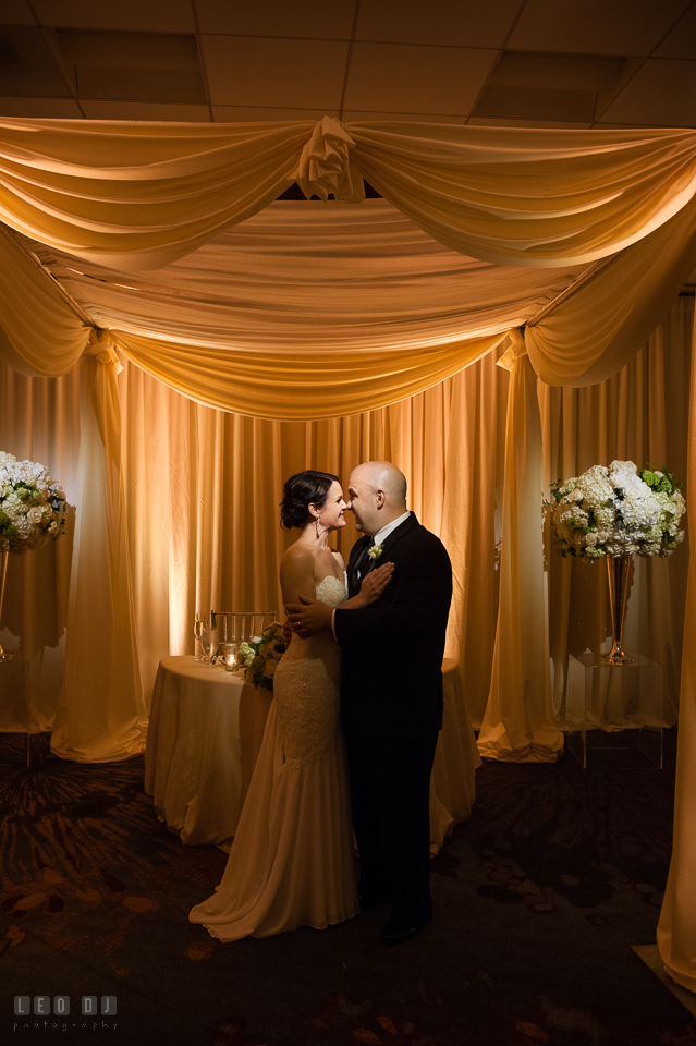 Westin Annapolis Hotel bride and groom hugging by sweetheart table under canopy photo by Leo Dj Photography