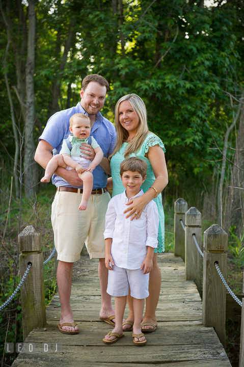 Family posing together on a small cross trail bridge. Chesapeake Bay, Kent Island, Annapolis, Eastern Shore Maryland children and family lifestyle portrait photo session by photographers of Leo Dj Photography. http://leodjphoto.com