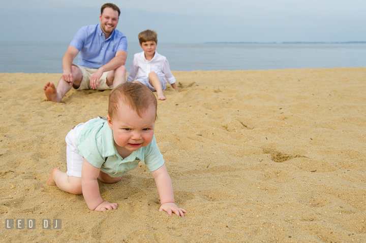 Baby boy crawling away from Father and older brother. Chesapeake Bay, Kent Island, Annapolis, Eastern Shore Maryland children and family lifestyle portrait photo session by photographers of Leo Dj Photography. http://leodjphoto.com