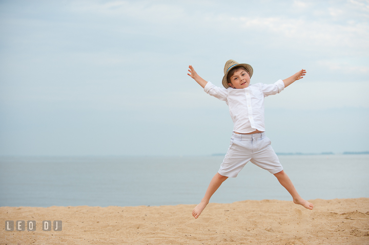 Little boy at the beach jumping high up in the air. Chesapeake Bay, Kent Island, Annapolis, Eastern Shore Maryland children and family lifestyle portrait photo session by photographers of Leo Dj Photography. http://leodjphoto.com