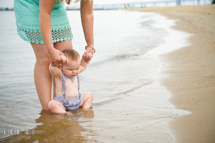 Mother holding child tasting the little water waves on the beach. Chesapeake Bay, Kent Island, Annapolis, Eastern Shore Maryland children and family lifestyle portrait photo session by photographers of Leo Dj Photography. http://leodjphoto.com