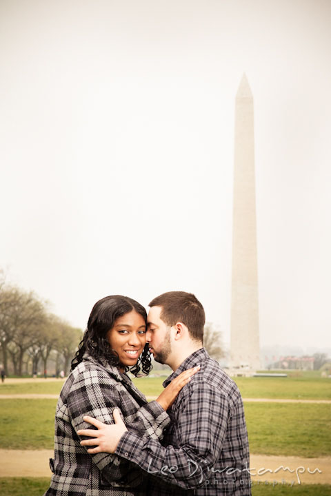 Engaged guy cuddled his fiancée with the National Monument in the background. Pre wedding engagement photo session the Mall, National Monument, The Capitol, Washington DC by wedding photographer Leo Dj Photography