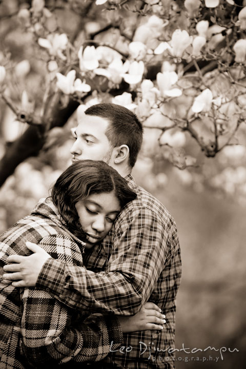 Engaged guy hugged his fiancée by a flowering magnolia tree. Pre wedding engagement photo session the Mall, National Monument, The Capitol, Washington DC by wedding photographer Leo Dj Photography