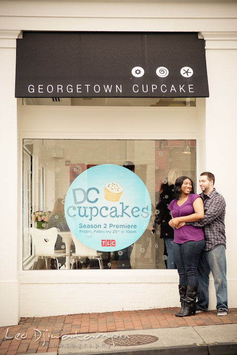 Engaged guy and girl cuddling by the Georgetown Cupcake shop, DC cupcake TLC sign. Pre wedding engagement photo session at Georgetown, Washington DC by wedding photographer Leo Dj Photography