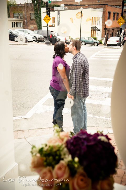 Engaged guy and his fiancée kissing outside on the street. Pre wedding engagement photo session at Georgetown, Washington DC by wedding photographer Leo Dj Photography