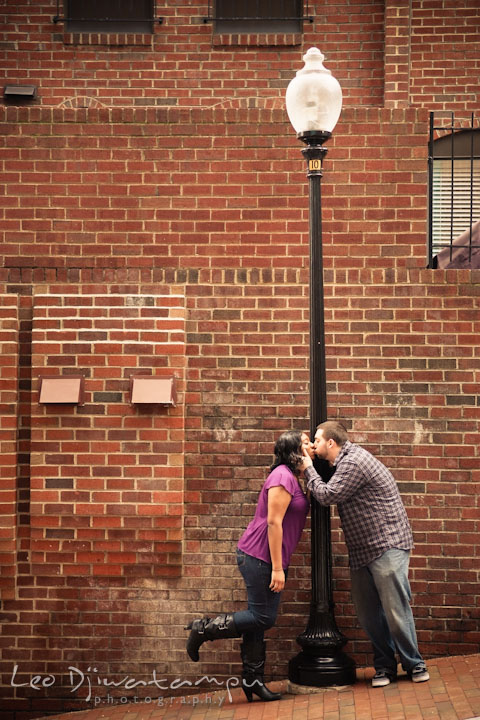 Engaged guy and girl kissing by a street light. Pre wedding engagement photo session at Georgetown, Washington DC by wedding photographer Leo Dj Photography