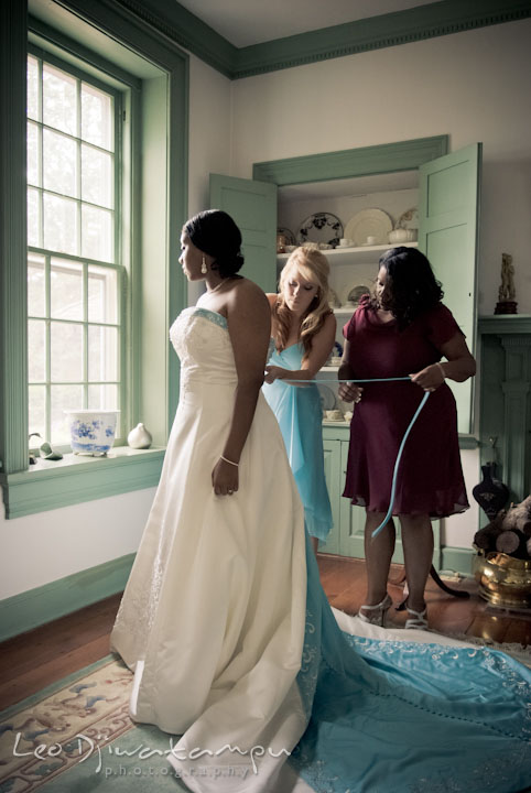 Mother and maid of honor help bride put on wedding dress. Kitty Knight House Georgetown Maryland wedding photos by photographers of Leo Dj Photography.
