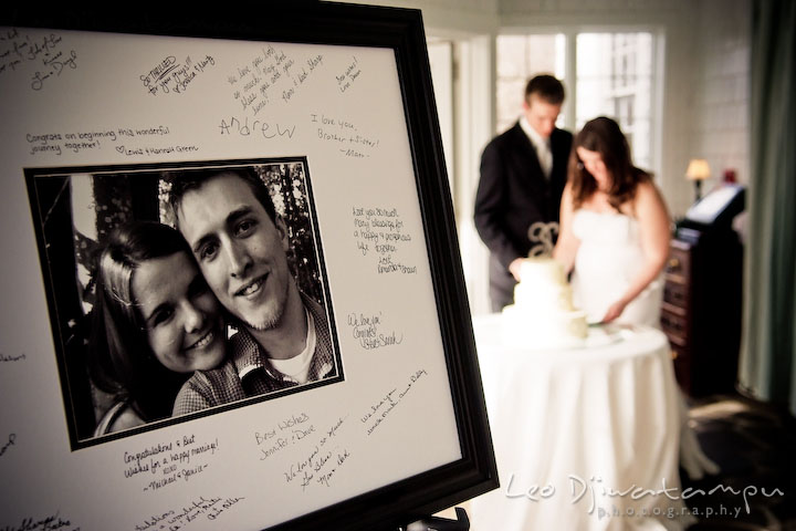 signature keepsake with engagement picture and guest signatures. bride and groom cutting wedding cake in the background. Clifton Inn Charlottesville VA Destination Wedding Photographer