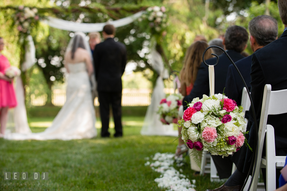 Floral decorations hanging on chairs in the aisle, Bride and Groom in the background. Aspen Wye River Conference Centers wedding at Queenstown Maryland, by wedding photographers of Leo Dj Photography. http://leodjphoto.com