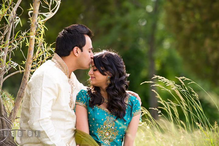 Engaged girl got kissed on her forehead by her fiancé. Indian pre-wedding or engagement photo session at Eastern Shore beach, Maryland, by wedding photographers of Leo Dj Photography.