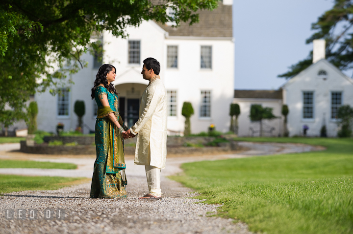 Engaged girl holding hands with her fiancé in front of an old mansion. Indian pre-wedding or engagement photo session at Eastern Shore beach, Maryland, by wedding photographers of Leo Dj Photography.
