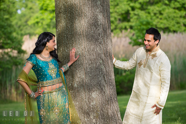 Engaged couple by a tree, looking at each other. Indian pre-wedding or engagement photo session at Eastern Shore beach, Maryland, by wedding photographers of Leo Dj Photography.