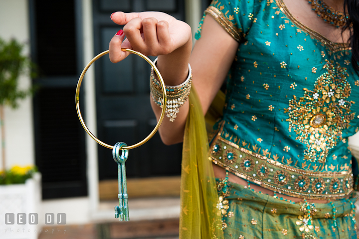 Engaged girl holds keys to the cuffs and ball chain on her fiancé. Indian pre-wedding or engagement photo session at Eastern Shore beach, Maryland, by wedding photographers of Leo Dj Photography.