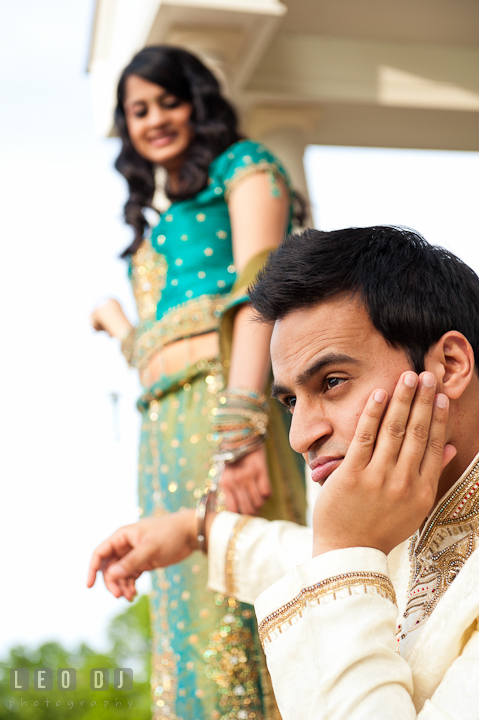 Engaged guy propped his chin while handcuffed to his fiancée. Indian pre-wedding or engagement photo session at Eastern Shore beach, Maryland, by wedding photographers of Leo Dj Photography.