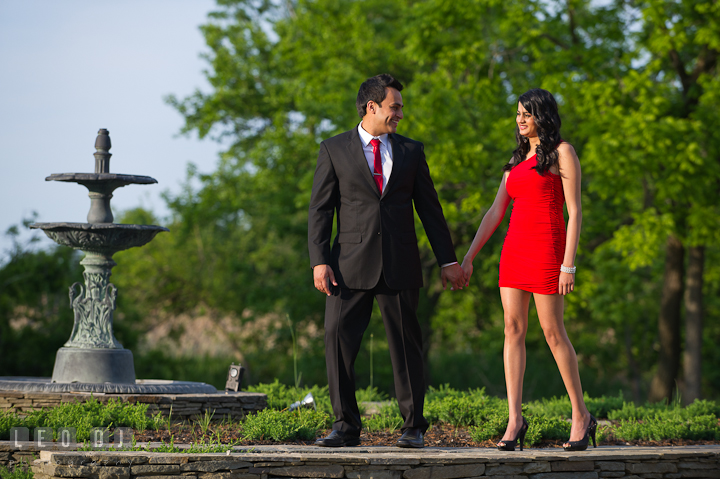 Engaged couple walking by the water fountain. Indian pre-wedding or engagement photo session at Eastern Shore beach, Maryland, by wedding photographers of Leo Dj Photography.