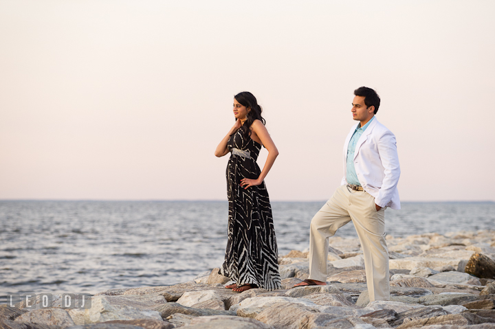 Engaged girl and her fiancé posing on the rocks at the beach. Indian pre-wedding or engagement photo session at Eastern Shore beach, Maryland, by wedding photographers of Leo Dj Photography.