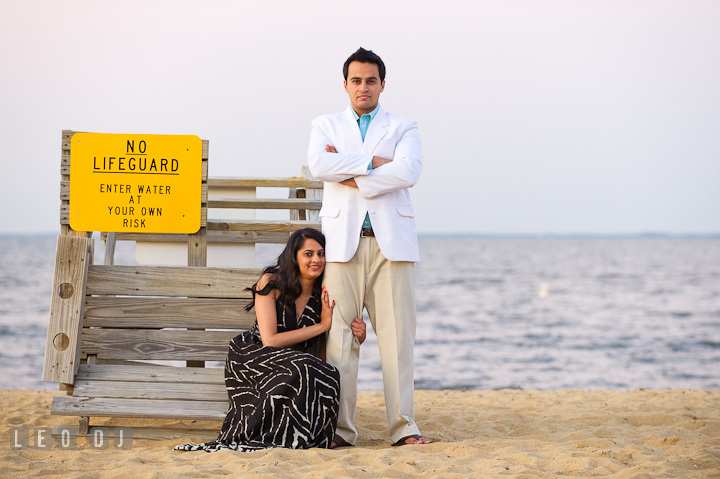 Engaged couple posing by a lifeguard shack. Indian pre-wedding or engagement photo session at Eastern Shore beach, Maryland, by wedding photographers of Leo Dj Photography.