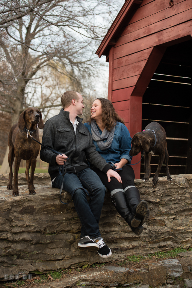 Baker Park Frederick Maryland engaged couple with dogs laughing by red bridge photo by Leo Dj Photography.