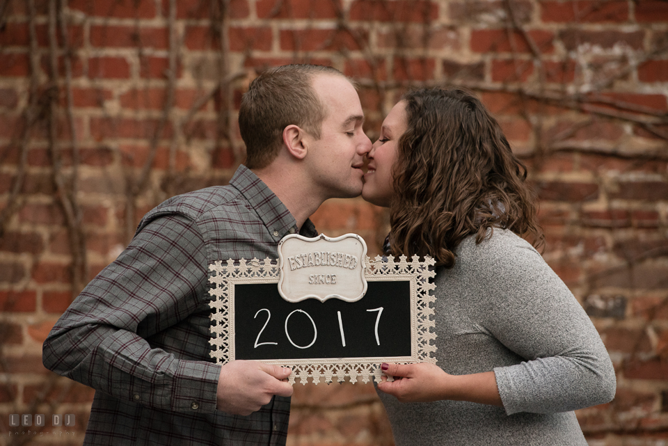 Downtown Frederick Maryland engaged couple holding wedding year sign photo by Leo Dj Photography.