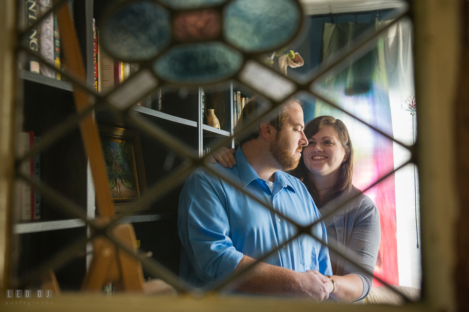 Home Residence Baltimore Maryland engaged couple hugging seen through stained window photo by Leo Dj Photography.