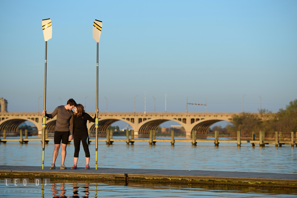 Baltimore Rowing Club Maryland engaged couple holding oars on dock by Hanover Street Bridge photo by Leo Dj Photography.