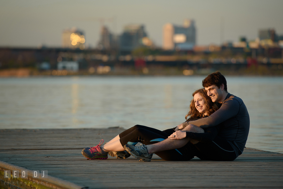 Baltimore Rowing Club Maryland engaged girl cuddling with fiancé on dock during sunset photo by Leo Dj Photography.