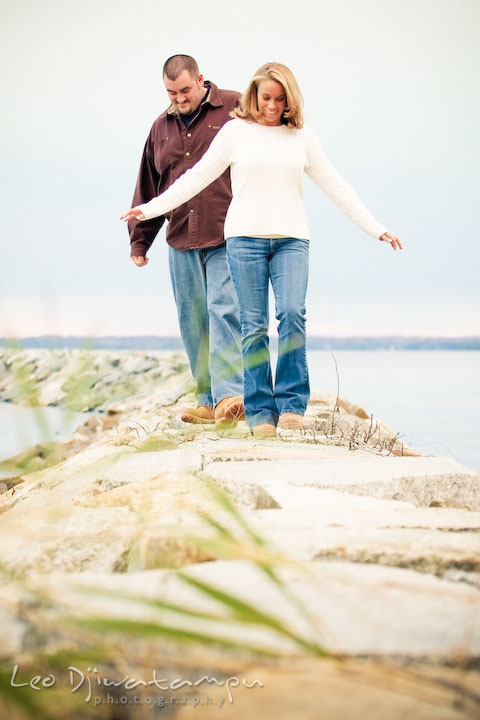 guy and girl walking on rocks by the water. Engagement Photographer Matapeake Beach, Chesapeake Bay